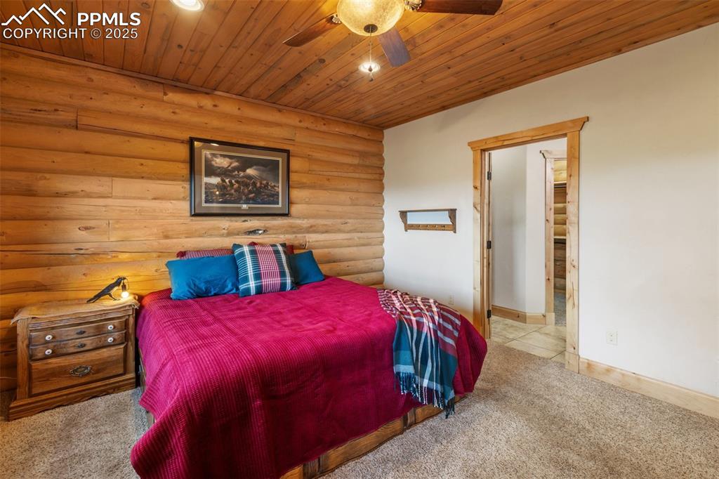 Carpeted bedroom featuring log walls, wooden ceiling, ceiling fan, and recessed lighting