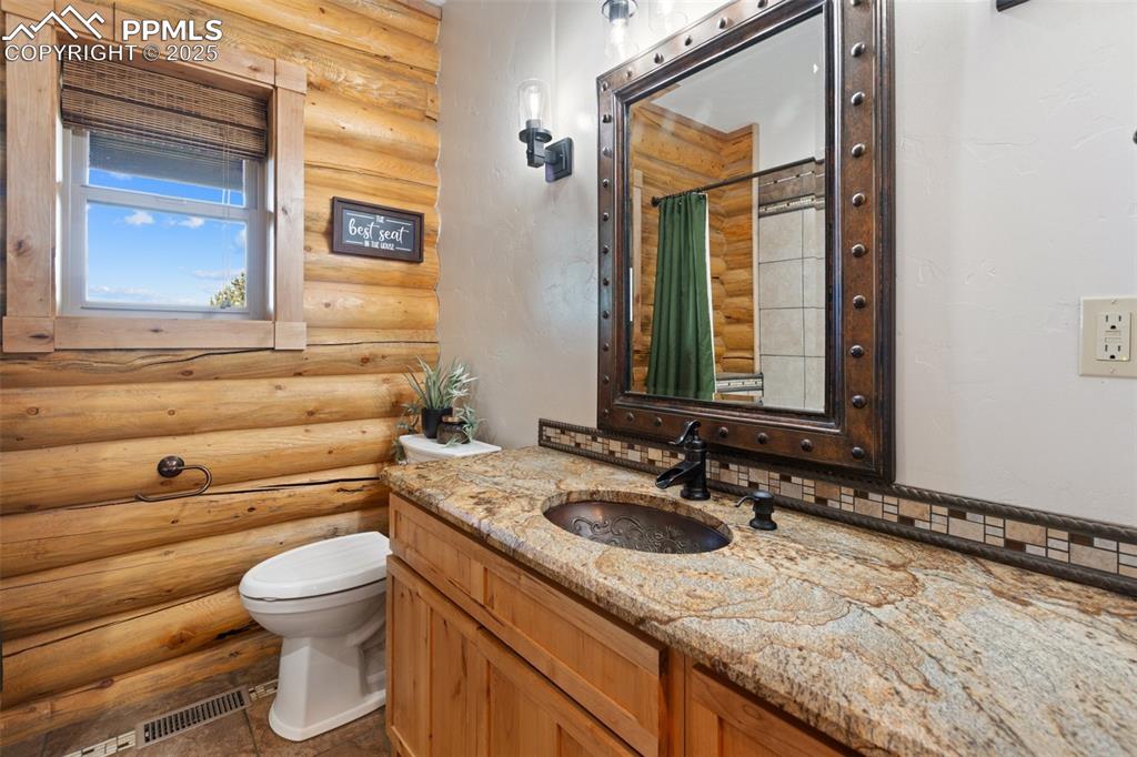 Bathroom with log walls, curtained shower, and vanity