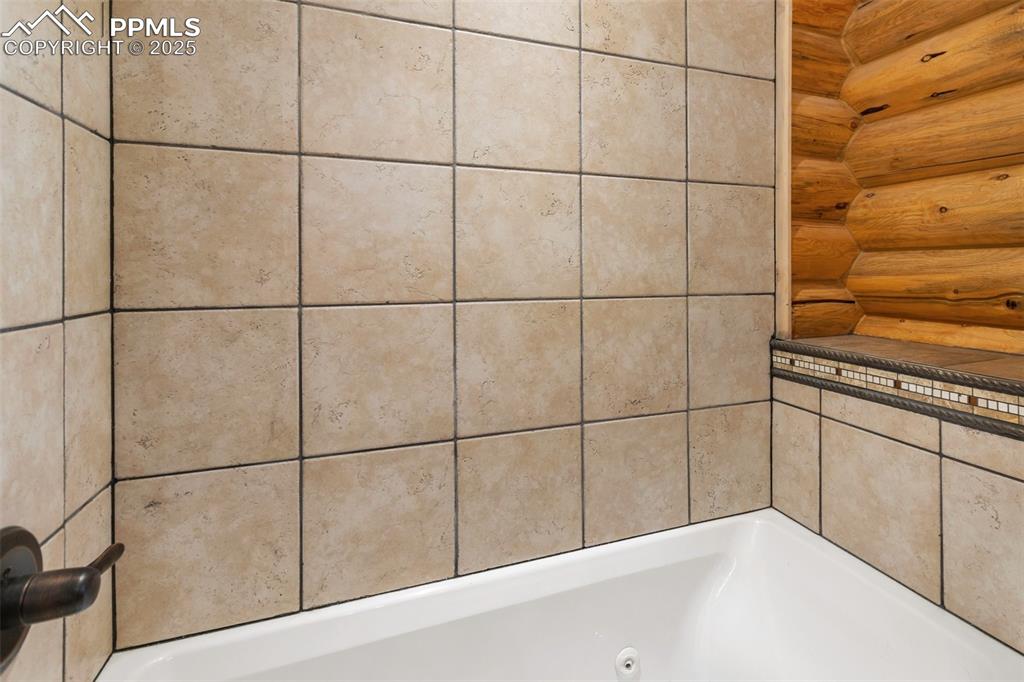 Full bathroom featuring a jetted tub and rustic walls