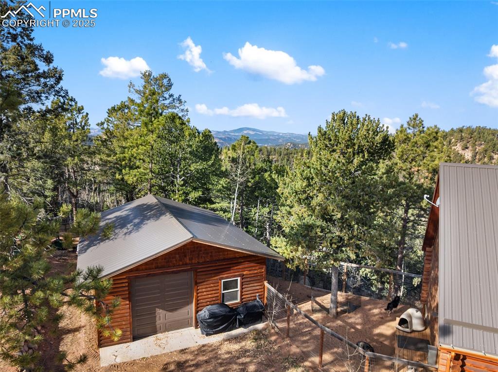 View of home's exterior with an outbuilding, a garage, faux log siding, and a forest view