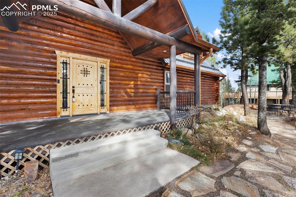 Entrance to property with log siding, a deck, and a patio area