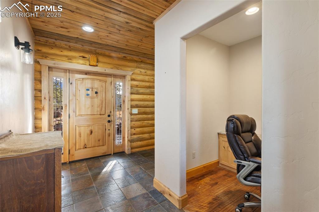 Foyer featuring wooden ceiling, recessed lighting, log walls, and stone tile flooring