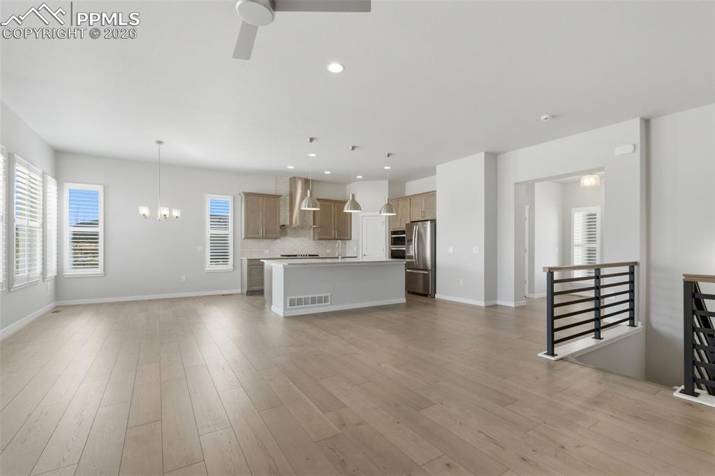Open-concept living room with luxury vinyl plank flooring, open staircase railing, and views into kitchen