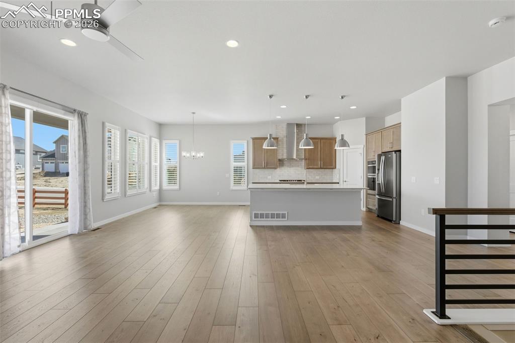 Expansive great room with luxury vinyl plank flooring, open staircase, and seamless flow to kitchen and dining