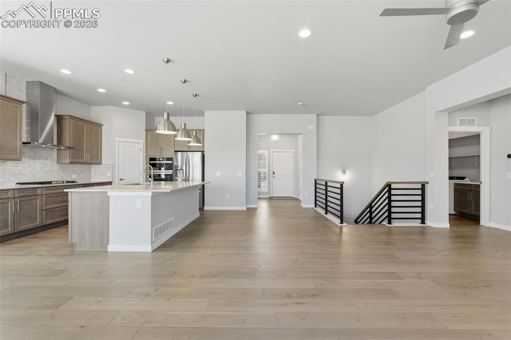 Chef's kitchen with large island, white quartz counters, custom cabinetry, and wide-plank hardwood floors