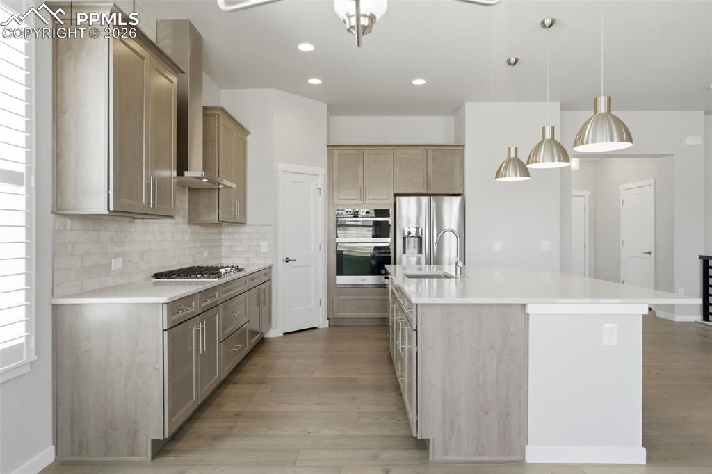 Beautiful kitchen with tall upper cabinets, stainless appliances, island seating, and subway tile backsplash