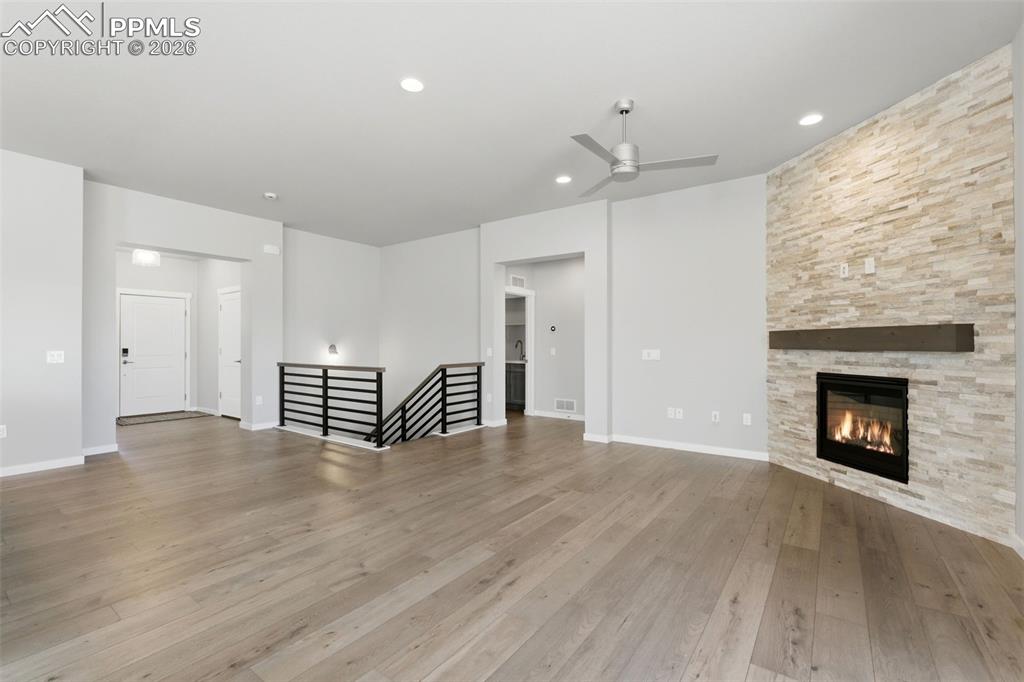 Inviting living room with stone fireplace surround, luxury vinyl plank flooring, and abundant natural light