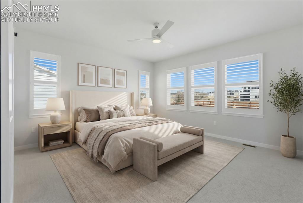 Virtually staged - Luxurious primary bedroom with large windows, ceiling fan, and a serene retreat atmosphere