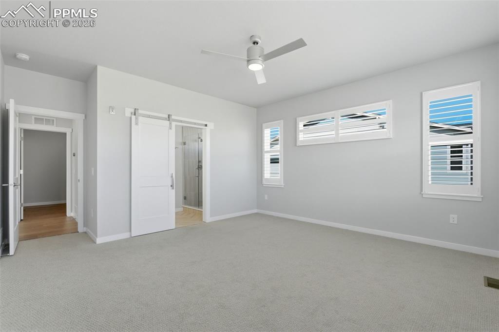 Generously sized bedroom with plush carpet, ceiling fan, and large windows with natural light