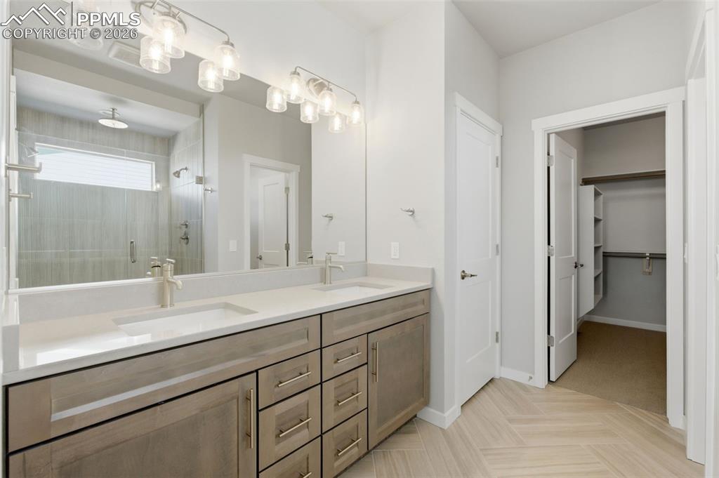 Primary bath with dual-sink vanity, recessed lighting, and walk-in closet access