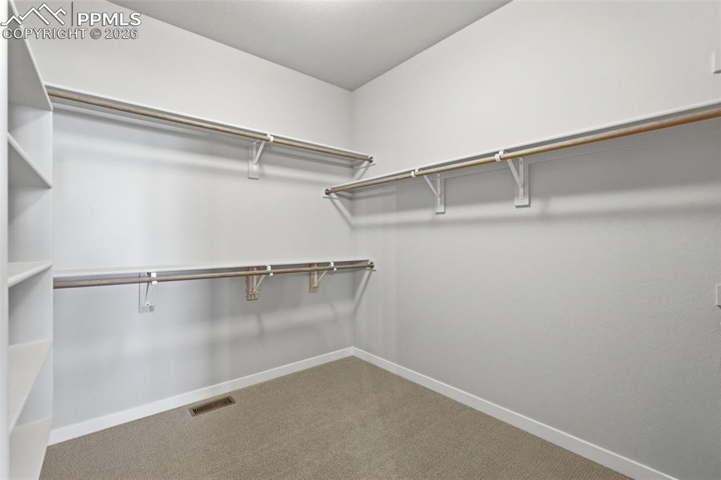 Generous walk-in closet with built-in shelving and rod system, providing excellent storage space