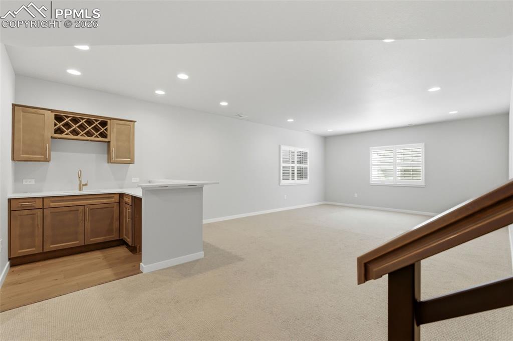 Stylish wet bar area in basement with custom wood cabinetry and counter seating - perfect for entertaining