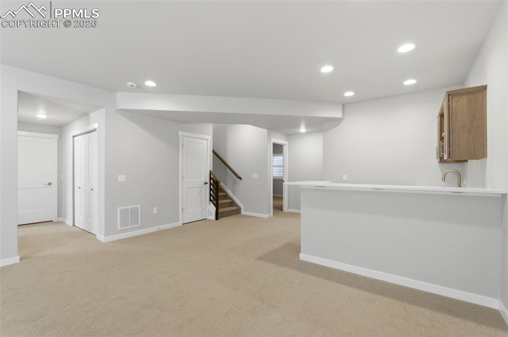 Finished basement area with recessed lighting, neutral carpet, and open layout for recreation or gym use