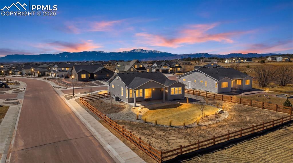 Back of home at dusk showcasing the covered deck, large windows, and beautiful Colorado sky