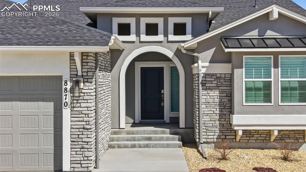 Grand entry with elegant arched doorway, stone exterior detail, and welcoming covered front porch