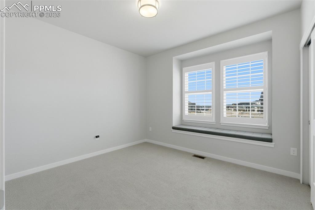 Versatile room with large windows, neutral carpet, and ample natural light - perfect for office or flex space