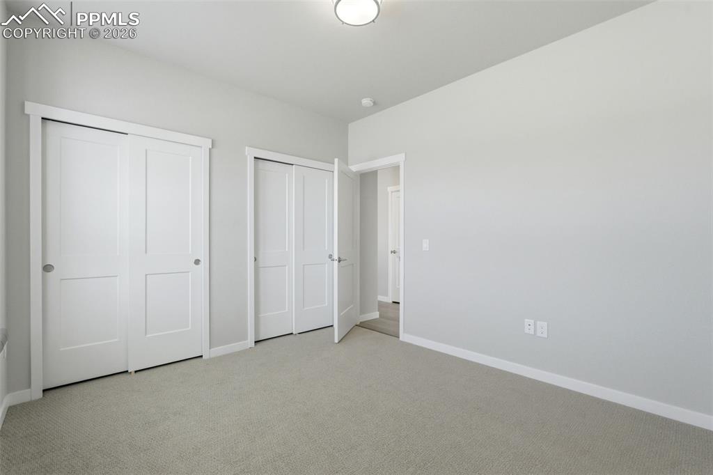 Spacious bedroom with neutral carpet, large closet with double doors, and plenty of natural light