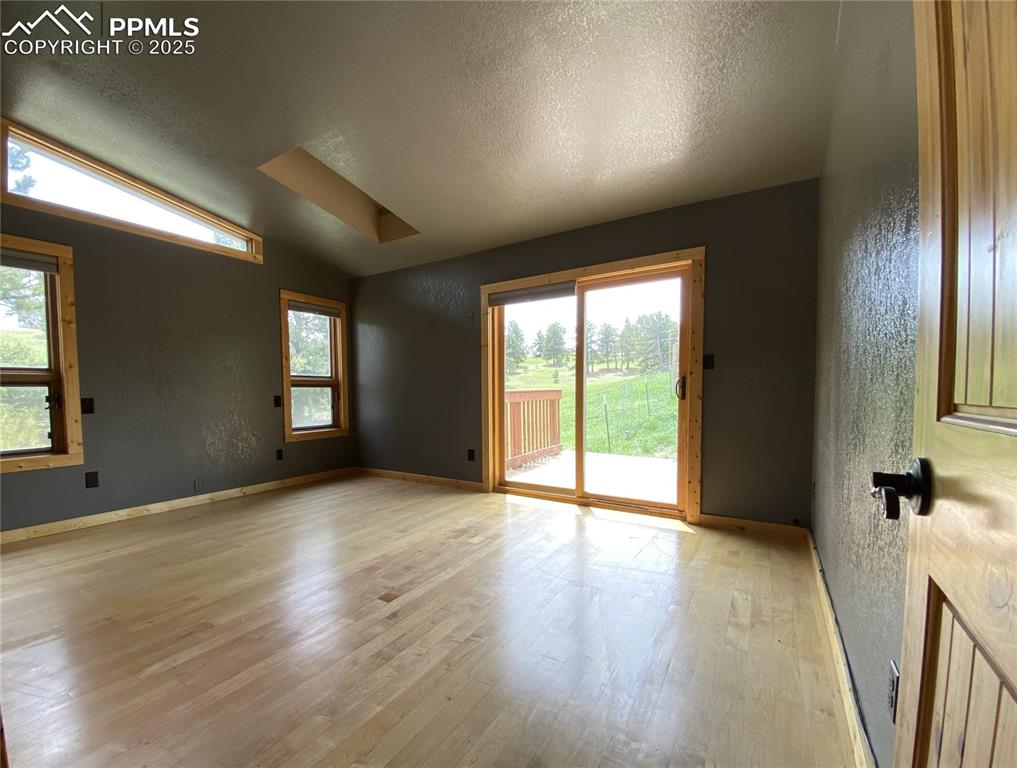 The primary bedroom featuring wood floors, lofted ceiling, with plenty of natural light