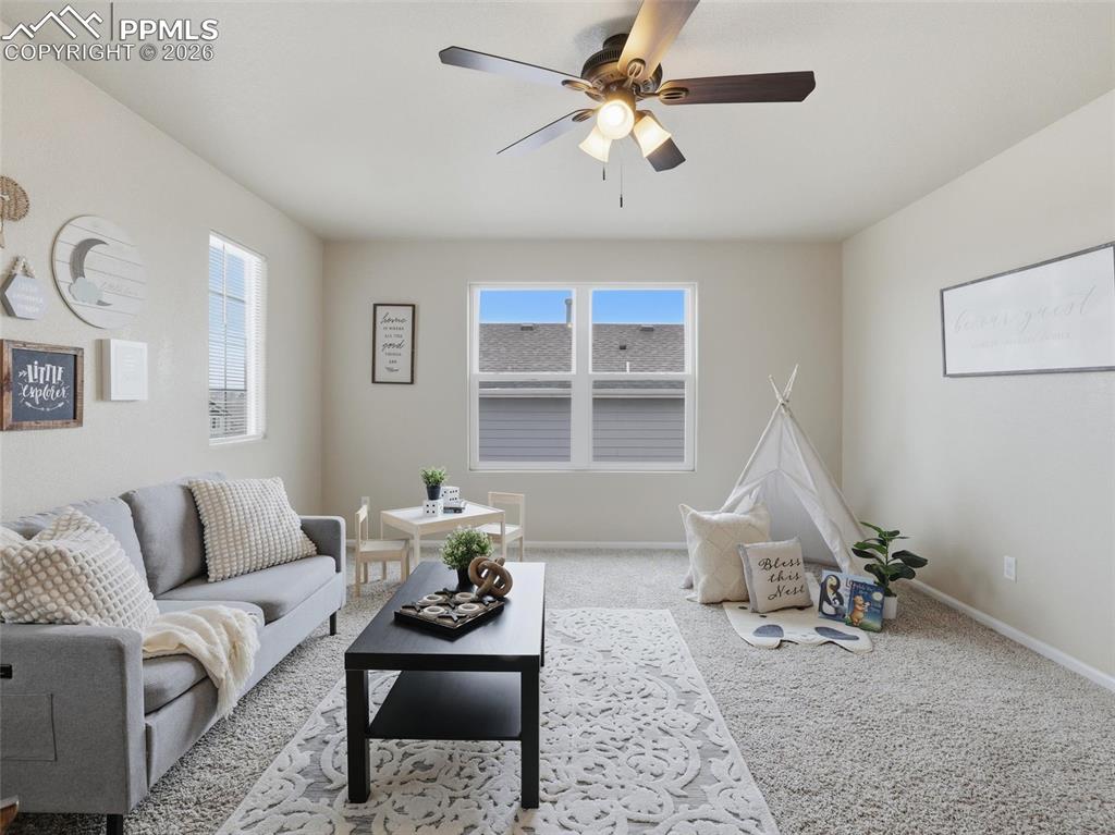 Carpeted living area featuring baseboards and ceiling fan