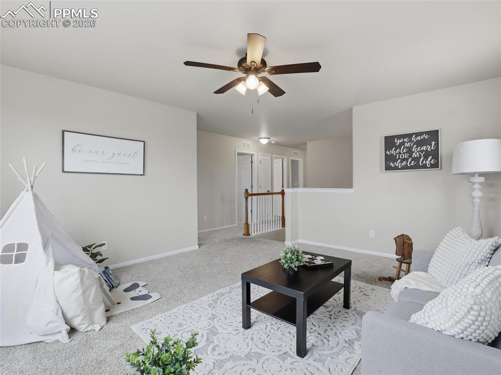 Carpeted living area with baseboards and a ceiling fan