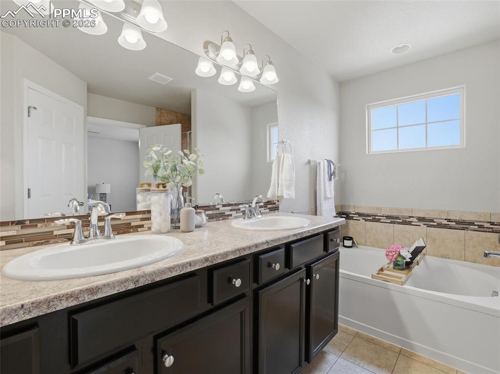 Full bath with a garden tub, double vanity, a stall shower, and light tile patterned flooring