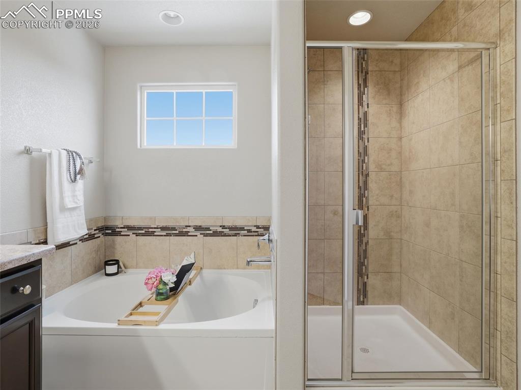 Full bath with a garden tub, a stall shower, vanity, and recessed lighting
