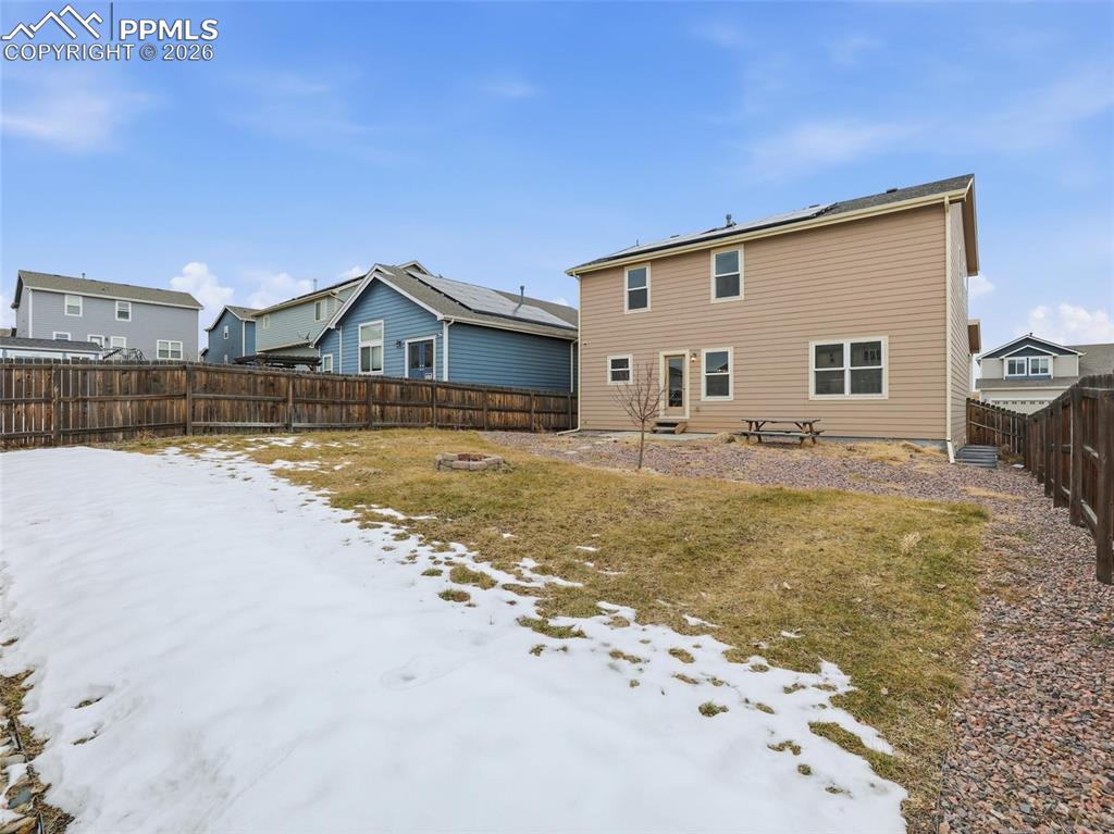 Snow covered house with a fenced backyard and a residential view