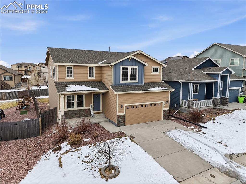 View of front of house with a porch, stone siding, concrete driveway, an attached garage, and board and batten siding