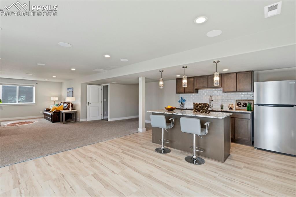 Kitchen with a kitchen bar, freestanding refrigerator, a kitchen island, open floor plan, and hanging light fixtures