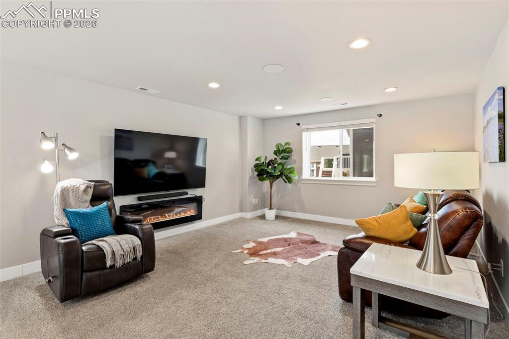 Carpeted living area featuring recessed lighting and a glass covered fireplace
