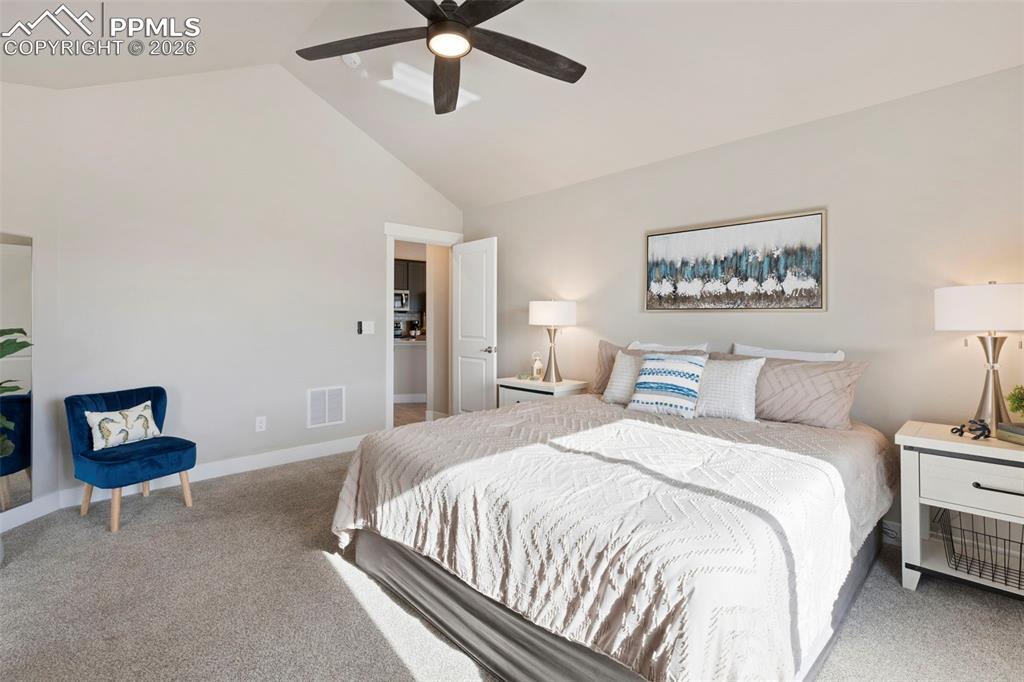 Bedroom with carpet, a ceiling fan, and a high ceiling