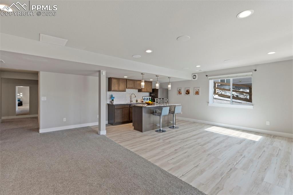 Basement Kitchenette with open floor plan, a breakfast bar area, a kitchen island, and light countertops