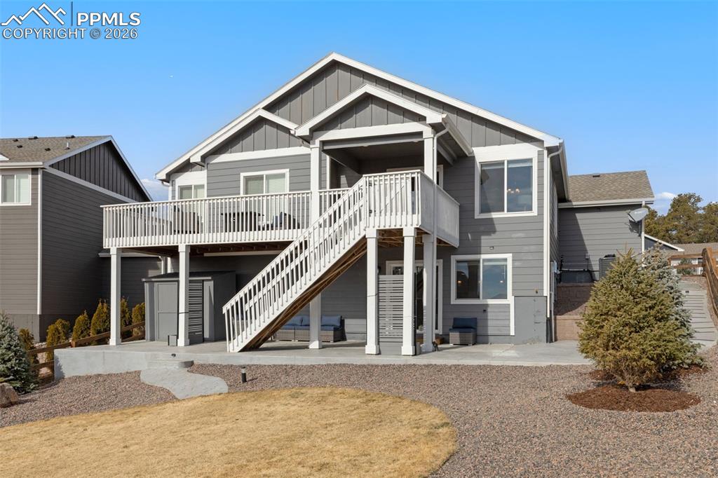 Back of property featuring a patio area, board and batten siding, and a wooden deck