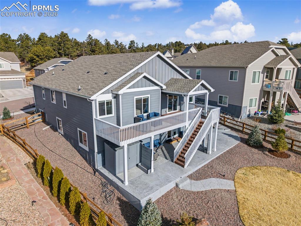 Back of house featuring board and batten siding, a wooden deck, a patio, a fenced backyard, and roof with shingles