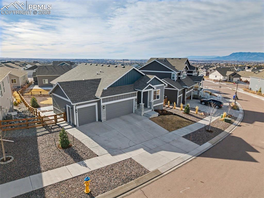 View of front of property with a residential view, a garage, concrete driveway, board and batten siding, and roof with shingles
