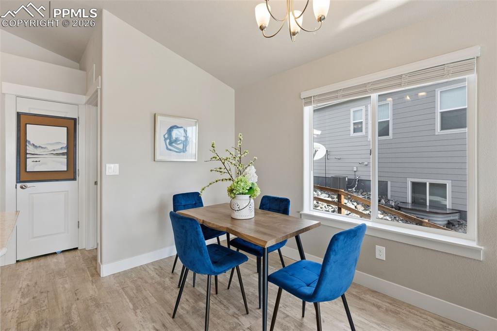 Dining space featuring lofted ceiling, light wood-type flooring, and a chandelier