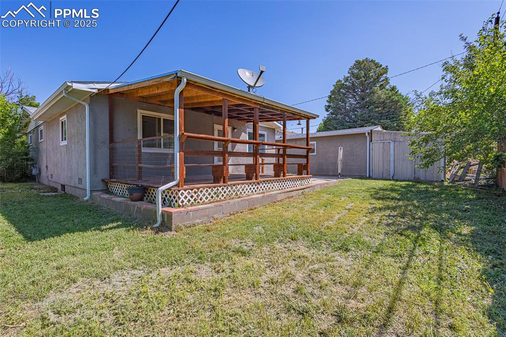 Back of house featuring a yard, stucco siding, and an outbuilding