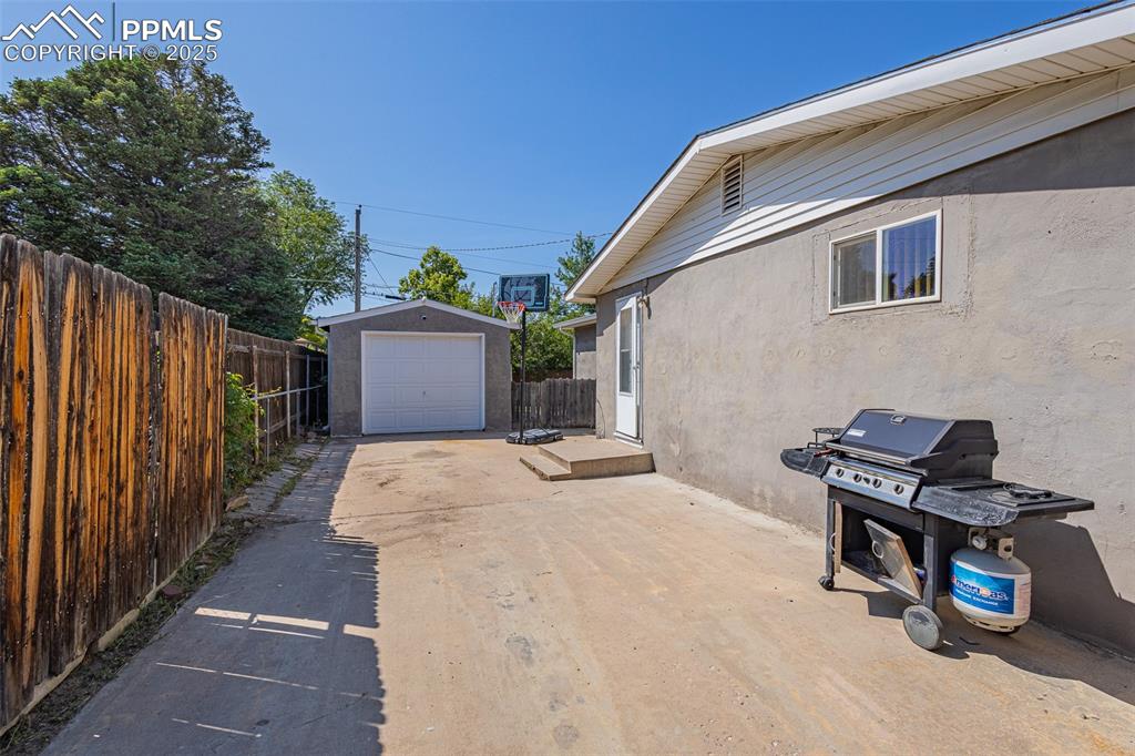 View of patio with area for grilling, a garage, driveway, and an outbuilding