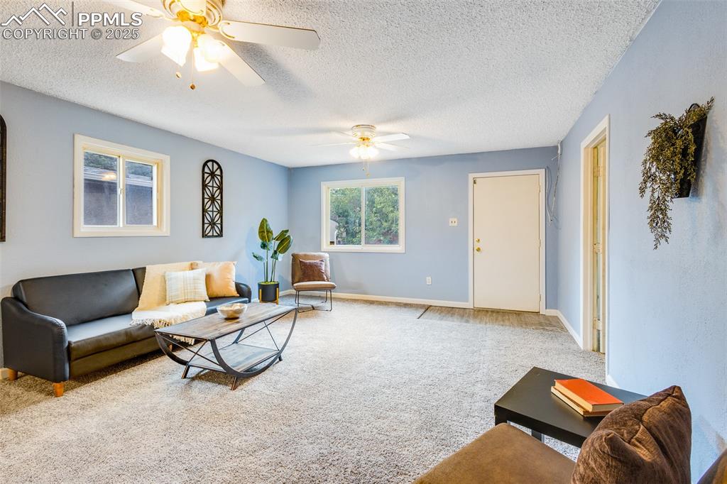 Carpeted living area featuring a textured ceiling and ceiling fan
