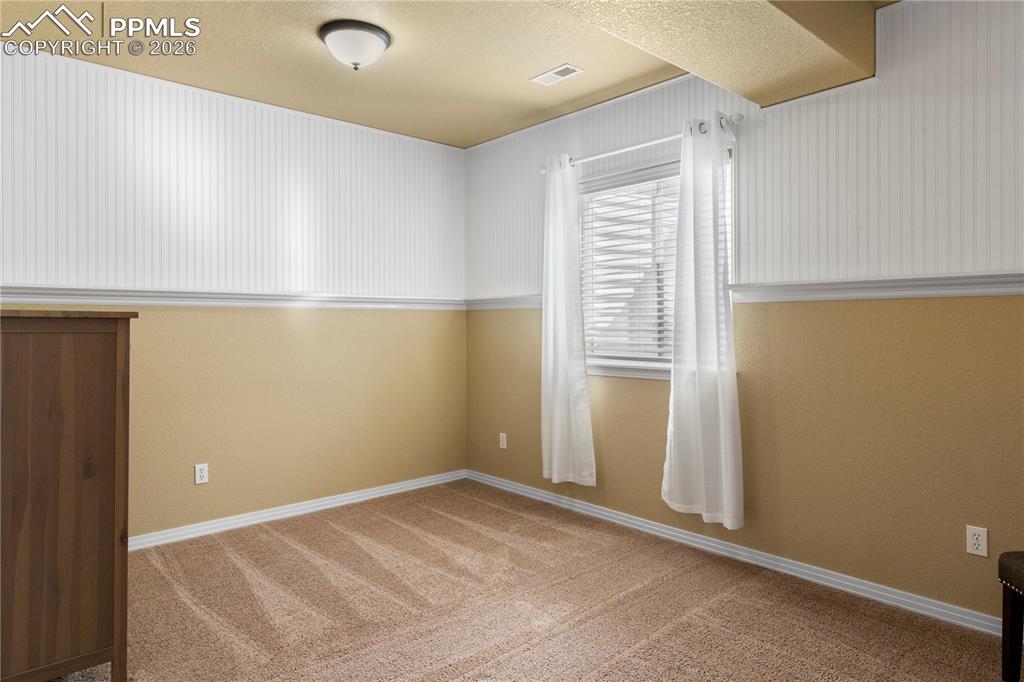 Basement bedroom with chair rail and wainscoting also features walk in closet. 