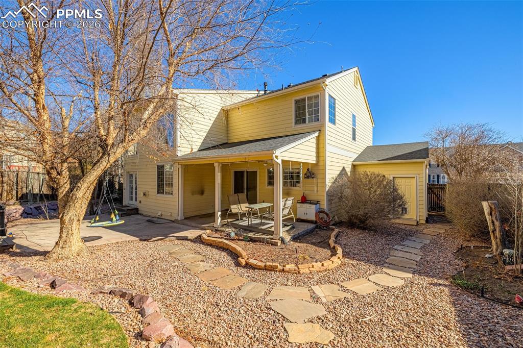 Mature landscape surrounds a flagstone patio and covered patio off the kitchen