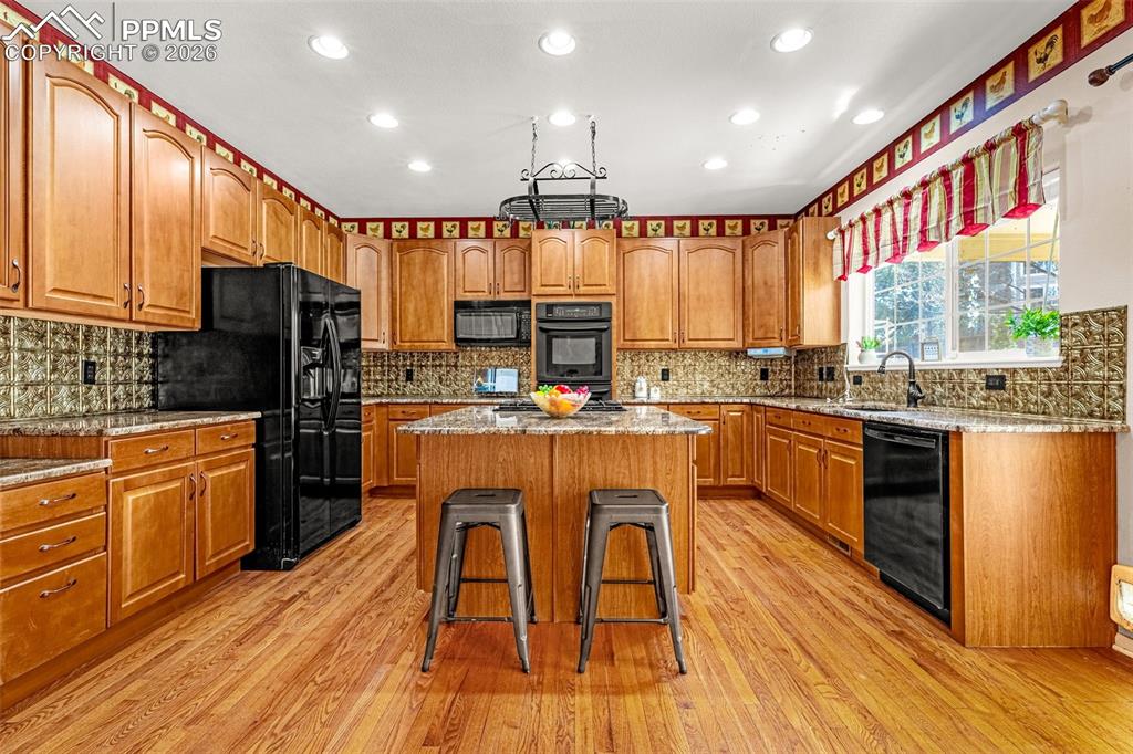 Exceptional natural wood kitchen accented with granite countertops and black appliances