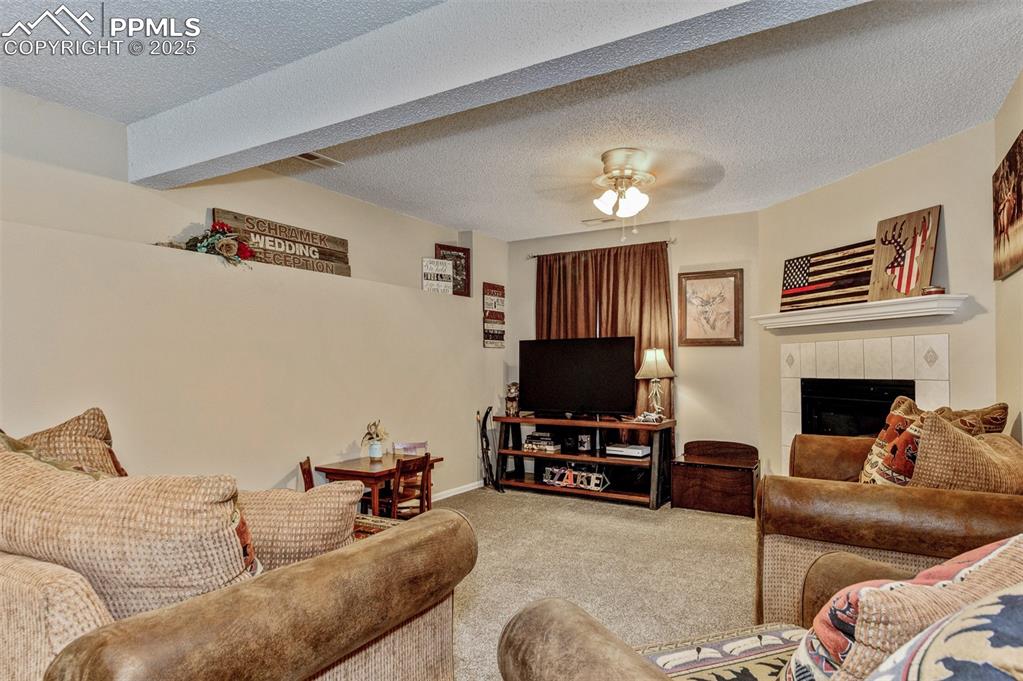 Carpeted family room on the lower level with a tiled fireplace