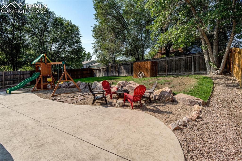 Fenced backyard featuring a playground and a patio area