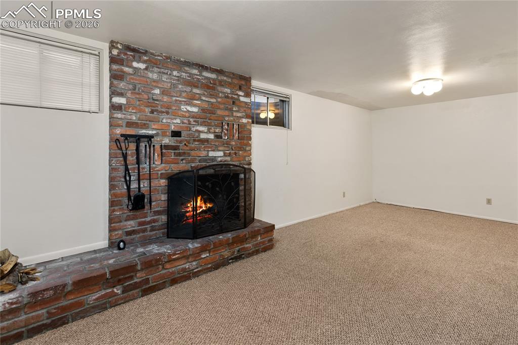 Basement family room features a wood burning fireplace. 