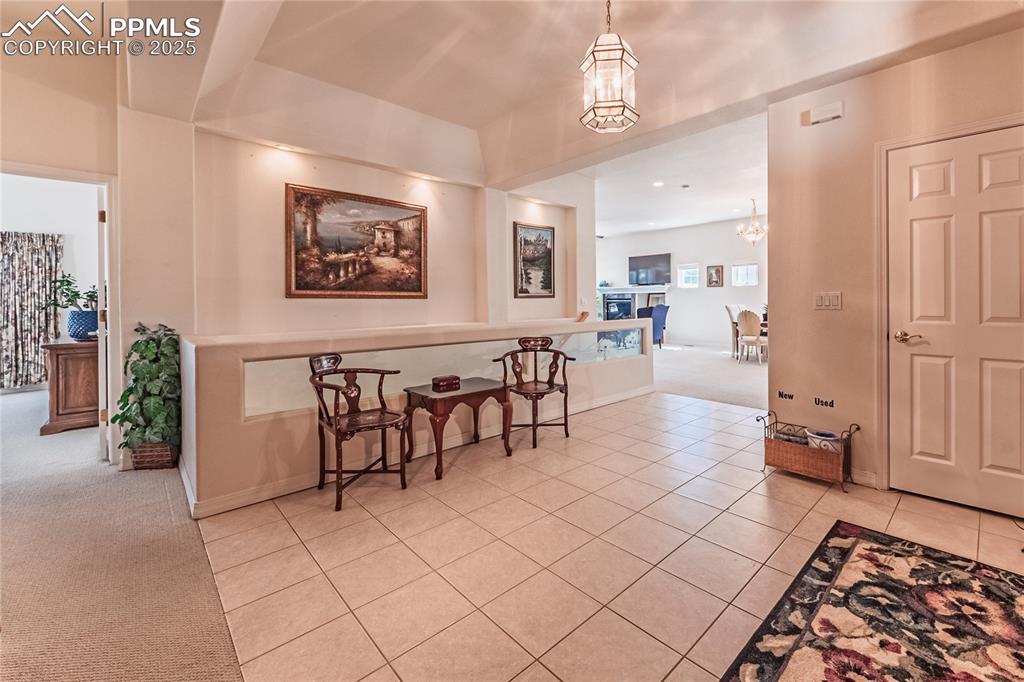 Dining space with light carpet, light tile patterned floors, and a chandelier