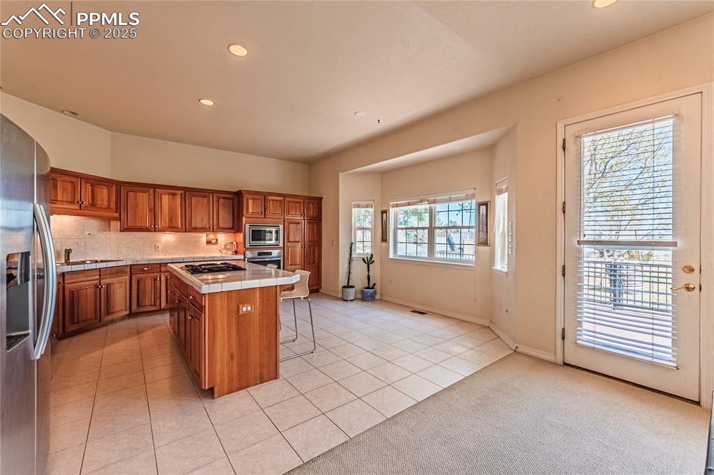 Kitchen with a breakfast bar, a center island, stainless steel appliances, brown cabinets, and tile counters