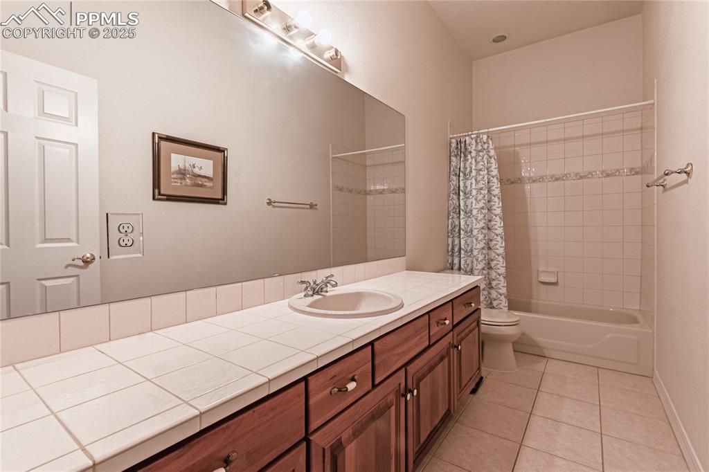 Full bathroom featuring vanity, tile patterned flooring, toilet, shower / bath combo with shower curtain, and baseboards