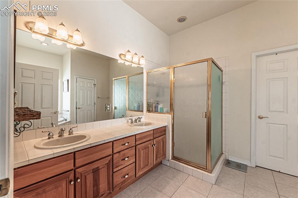Full bathroom with a shower stall, double vanity, and a sink