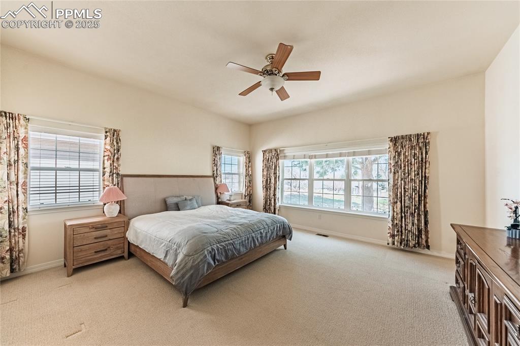 Bedroom featuring light colored carpet, baseboards, a ceiling fan, and visible vents